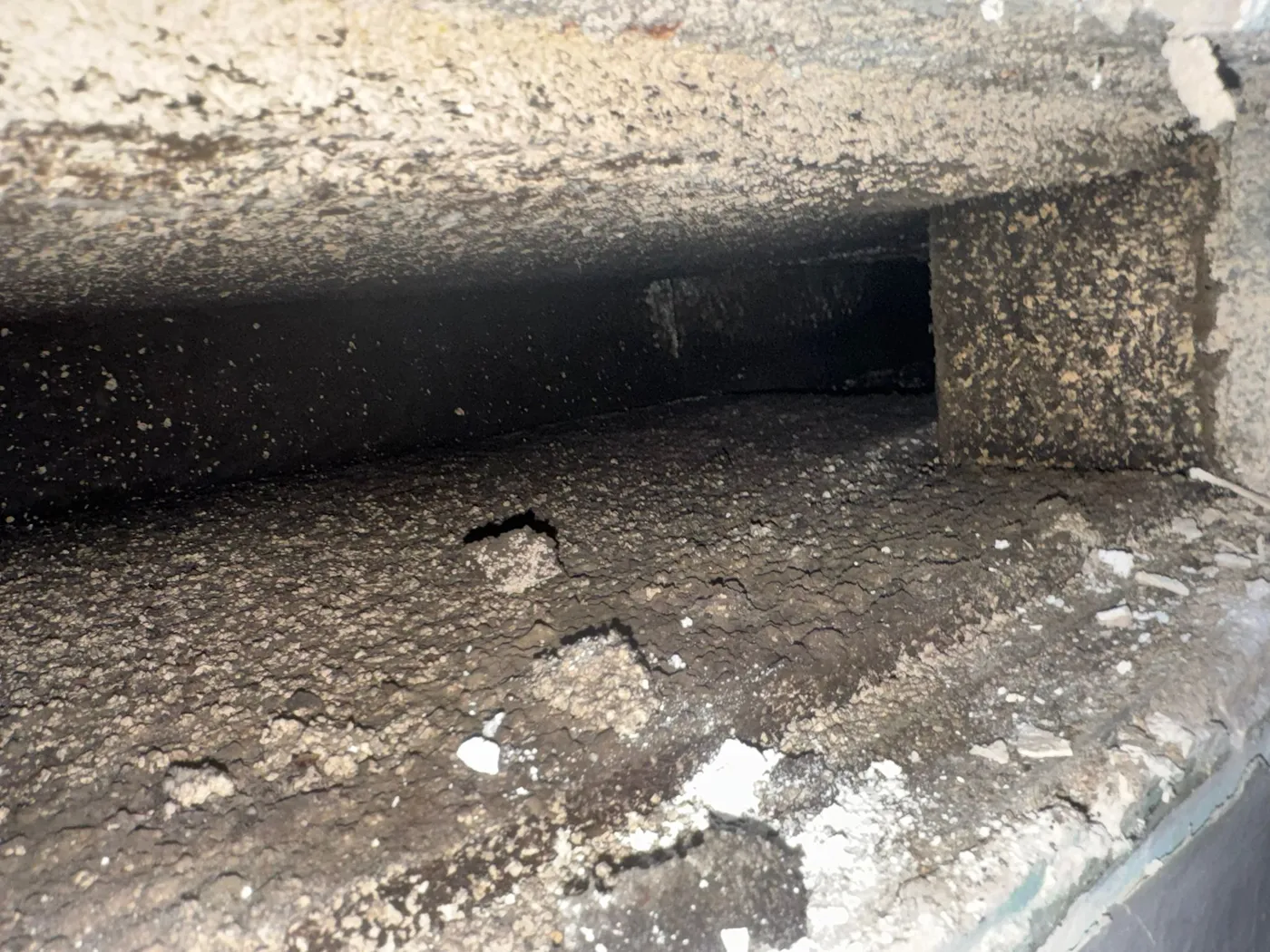 Main supply duct coated in black debris before cleaning